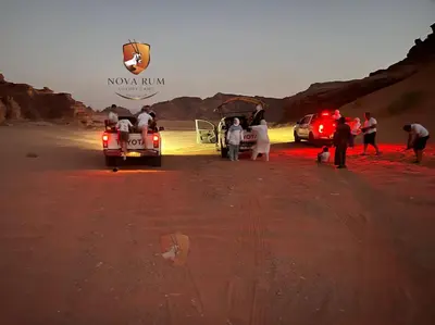 a group of people standing around a truck in the desert at Nova Rum Luxury Camp in Disah