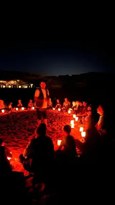 a group of people sitting on a beach with candles at Bright Moon Luxury Camp in Wadi Rum