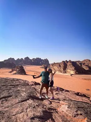 a man and woman standing on a rock in the desert at Bright Moon Luxury Camp in Wadi Rum