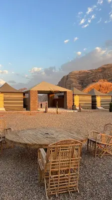 a wooden table and chairs in front of a building at Bright Moon Luxury Camp in Wadi Rum