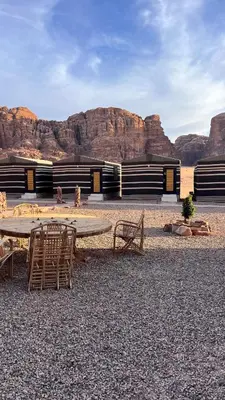a building with a table and chairs in the desert at Bright Moon Luxury Camp in Wadi Rum