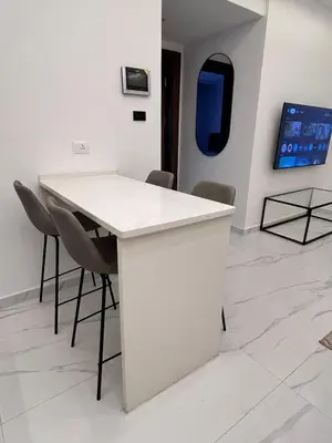 a white table and chairs in a room with a tv at Luxurious 2 bedroom furnished apartment in Abdoun in Amman