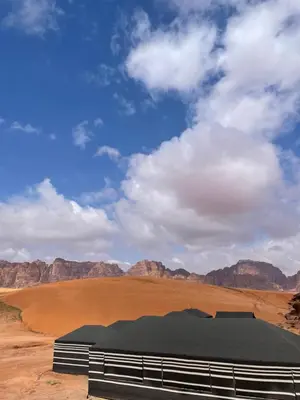 a building in the middle of a desert with mountains at Red Dunes Wadi Rum Camp in Wadi Rum