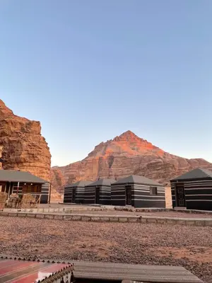a row of buildings with mountains in the background at Red Dunes Wadi Rum Camp in Wadi Rum