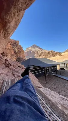 a person laying on a bench with a table in the desert at Red Dunes Wadi Rum Camp in Wadi Rum
