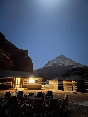 a group of chairs in front of a building with a mountain at Red Dunes Wadi Rum Camp in Wadi Rum