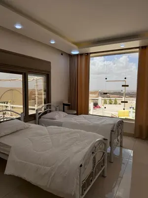 two beds in a room with a large window at Milano villa & farm in Balīlā