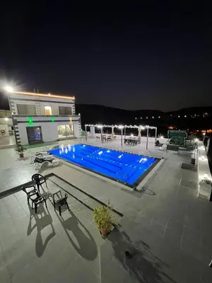 a large blue swimming pool on a building at night at panorama tal elroman chalet in Tal‘at ar Ruzz