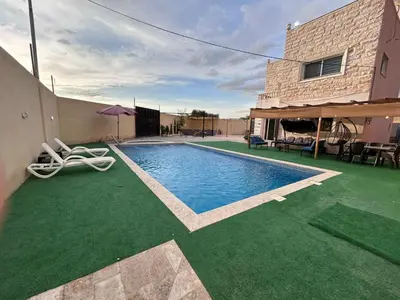 a house with a swimming pool with green grass at Entire Home Near Deadsea & Baptism Site Pool, Garden, BBQ, Great Price in Shūnat Nimrīn