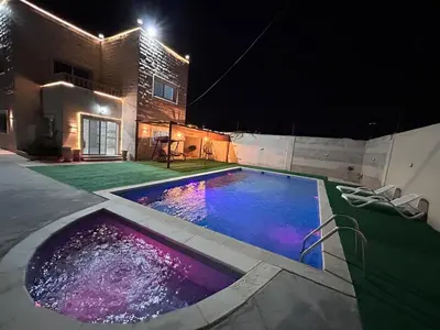 a swimming pool with purple lights in a yard at night at Entire Home Near Deadsea & Baptism Site Pool, Garden, BBQ, Great Price in Shūnat Nimrīn