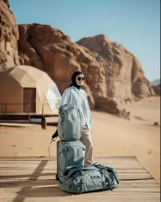 a man standing next to a bag in the desert at RUM lUXURY SAMA CAMP in Wadi Rum