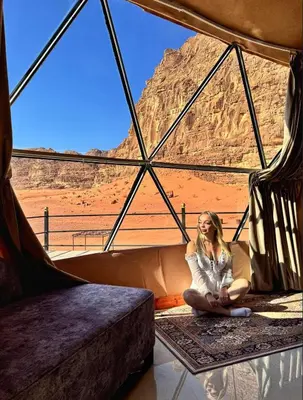 a woman sitting in a tent looking out at the desert at RUM lUXURY SAMA CAMP in Wadi Rum