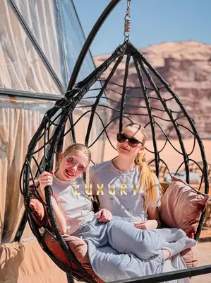 two girls are sitting in a swing at RUM CROWD DARLiNG LUXURY in Wadi Rum