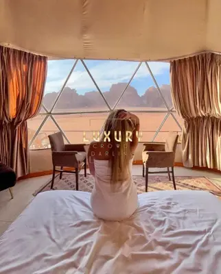 a woman sitting on a bed in front of a window at RUM CROWD DARLiNG LUXURY in Wadi Rum