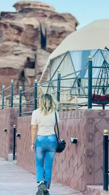 a woman walking down a sidewalk next to a wall at RUM CROWD DARLiNG LUXURY in Wadi Rum