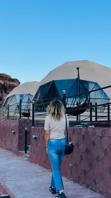 a woman walking down a sidewalk next to a wall at RUM CROWD DARLiNG LUXURY in Wadi Rum