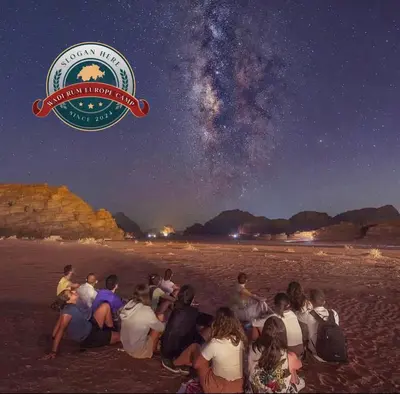 a group of people sitting on the beach at night at WADI RUM EUROPE lUXURY CAMP in Wadi Rum