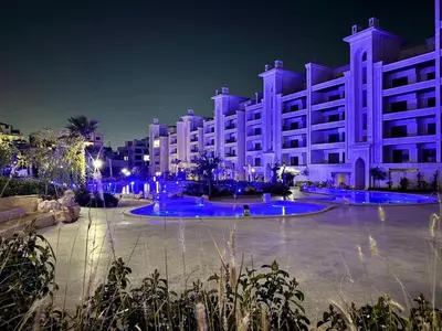 a large white building at night with blue lights at The Boulevard Residences in Amman