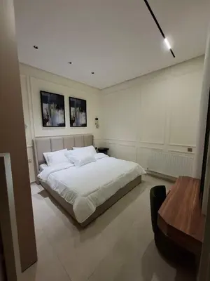 a bedroom with a white bed and a wooden table at The Boulevard Residences in Amman