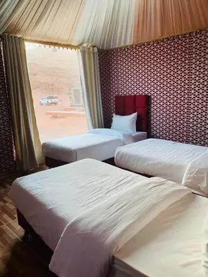 a bedroom with two beds and a window with a car at Suleman Camp in Wadi Rum