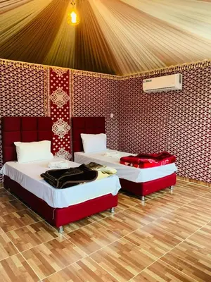 two beds in a room with red and white at Suleman Camp in Wadi Rum
