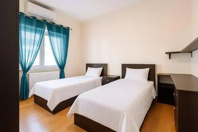 two beds in a room with blue curtains at The Central Family Apartment in Amman