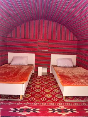 two beds in a room with a red wall at Camp in the natural reserve & tours in Aqaba