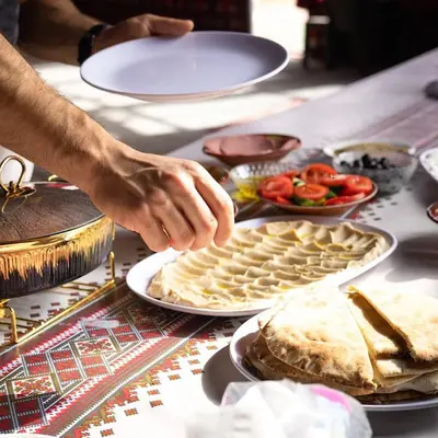 a person reaching for a plate of food on a table at Camp in the natural reserve & tours in Aqaba