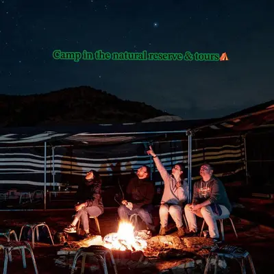 a group of people sitting around a fire at Camp in the natural reserve & tours in Aqaba