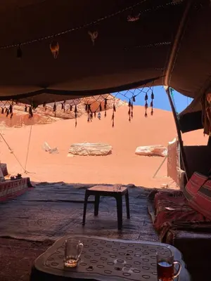a tent with a table and people on the beach at Sahara Camp Wadi Rum in Wadi Rum