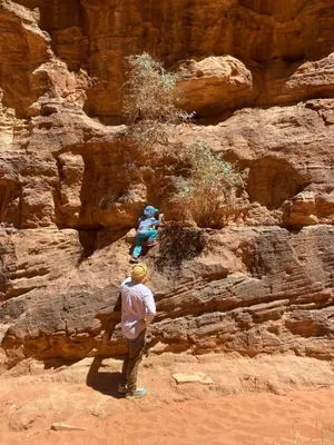 a man standing on top of a rocky mountain at Sahara Camp Wadi Rum in Wadi Rum