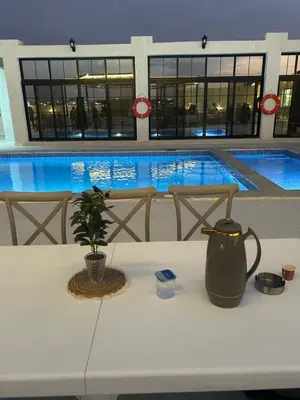 a table with a vase on it in front of a swimming pool at Olive tree chalet and farm -مزرعه و شاليه شجره الزيتون