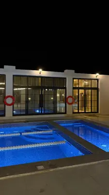 a large swimming pool at night with two red circles at Olive tree chalet and farm -مزرعه و شاليه شجره الزيتون