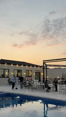 a group of people standing next to a swimming pool at olive tree farm and chalet - مزرعه و شاليه شجره الزيتون