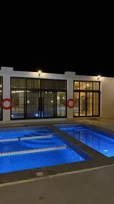 a large swimming pool at night in a building at olive tree farm and chalet - مزرعه و شاليه شجره الزيتون