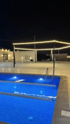 a large swimming pool at night with at olive tree farm and chalet - مزرعه و شاليه شجره الزيتون