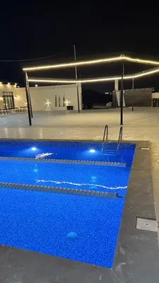 a large blue swimming pool at night at olive tree farm and chalet - مزرعه و شاليه شجره الزيتون