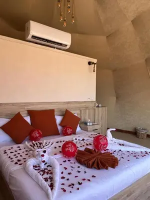 a bed with red decorations on top of it at Dania Luxury Camp in Wadi Rum