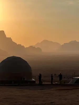 a group of people standing in the desert at sunset at Dania Luxury Camp in Wadi Rum