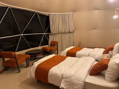 a hotel room with two beds and a table and chairs at Wadi rum Jad luxury camp in Wadi Rum