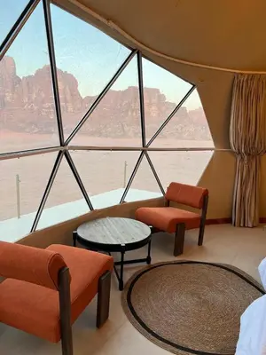 a room with a large window with chairs and tables at Wadi rum Jad luxury camp in Wadi Rum