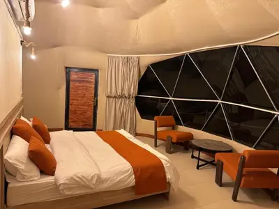 a bedroom with a bed and a large window at Wadi rum Jad luxury camp in Wadi Rum