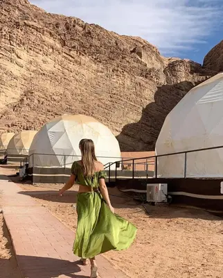 a woman in a green dress walking in the desert at Wadi rum Bubble Bianca luxury in Wadi Rum