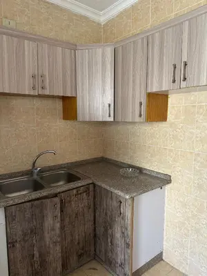 a kitchen with wooden cabinets and a sink at الجبيهة 2 نوم aljubiha apartment in Amman