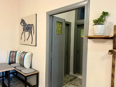 a door leading into a room with a chair and a horse picture at Spacious central apartment in Amman