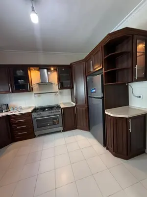 a kitchen with wooden cabinets and a stove and refrigerator at 3bedroom aprt of 200sqm near movenpick hotel amman in Amman