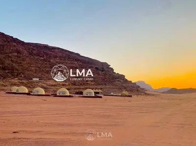 a building in the desert with the sunset in the background at LMA Rum Luxury Camp in Wadi Rum