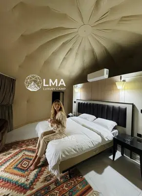 a woman sitting on a bed in a hotel room at LMA Rum Luxury Camp in Wadi Rum