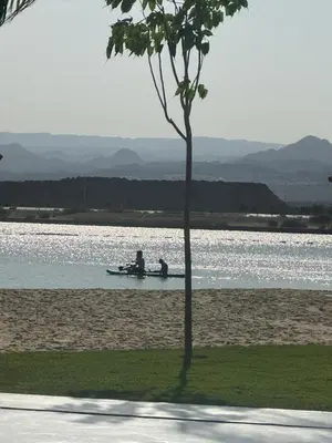 two people in a boat in the water near a tree at شقه شاطئيه in Aqaba