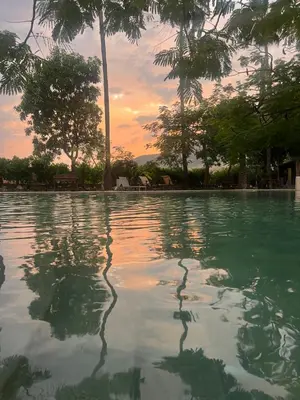 a pool of water with a sunset in the background at Sossita Guesthouse & Boutique Resort